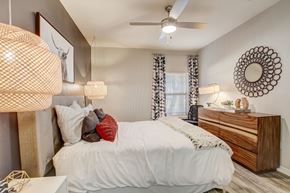 Kyle apartment for rent - A bedroom with a white bed and a wooden dresser.