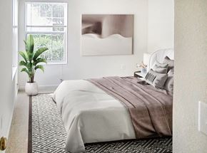Warrenton apartment for rent - A bedroom with a large bed and a plant on the side table.