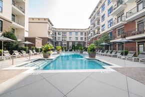 Knoxville apartment for rent - A large swimming pool surrounded by lounge chairs and umbrellas in a courtyard.