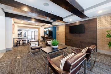 Knoxville apartment for rent - A modern living room with a brown leather couch and a flat screen TV mounted on the wall.