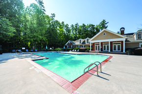 Kennesaw apartment for rent - A large swimming pool surrounded by a red border and a house in the background.