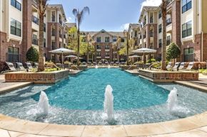 Houston apartment for rent - a pool with water fountains and a brick building in the background