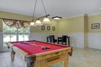 A pool table with a red cloth and a pool cue on it.