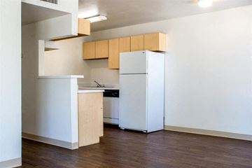 Tucson apartment for rent - A kitchen with a white fridge and wooden cabinets.