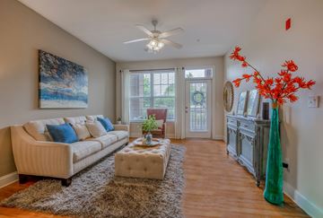 Concord apartment for rent - A living room with a beige couch, a brown rug, and a painting on the wall.