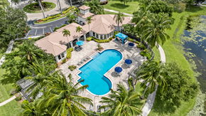 Boynton Beach apartment for rent - A large clubhouse with a pool and palm trees.