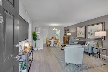Raleigh apartment for rent - A well-lit living room with a grey sofa, a yellow dining table, and a grey rug.