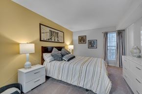 Raleigh apartment for rent - A bedroom with a bed, nightstand, and a painting on the wall.