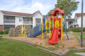 Hanahan apartment for rent - A red slide is the centerpiece of a playground in front of apartment buildings.