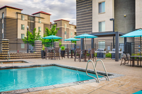 Murray apartment for rent - Swimming pool with tanning deck, tables and chairs with blue umbrellas surrounded by native landscape and building exterior