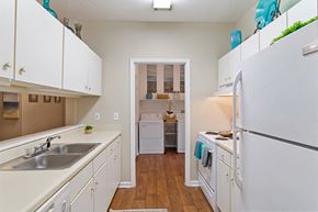 Warner Robins apartment for rent - Kitchen with white shaker cabinets, white appliances, and view laundry room in the background