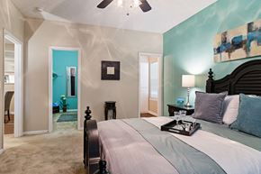 Warner Robins apartment for rent - carpeted bedroom with bed, art on the wall and view of bathroom and closet in the background