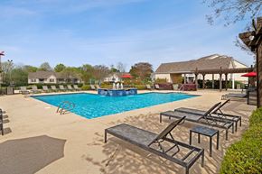 Warner Robins apartment for rent - Community pool with sundeck, lounge chairs, surrounded by black metal fence with trees, and building exteriors in the background