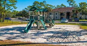 Greenacres apartment for rent - Fenced in Playground on Sand with Parking Lot and Building  in the Background