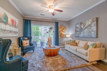 Frederick apartment for rent - A living room with a black leather chair, a wooden coffee table, a white couch, and a painting on the wall.