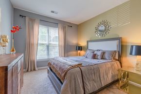 Frederick apartment for rent - A bedroom with a large bed and a clock on the wall.