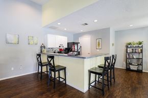 Sanford apartment for rent - Clubhouse kitchen with white cabinets, grey countertops, breakfast bar with 4 barstools, coffee station and black appliances