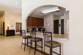 Bradenton apartment for rent - Clubhouse kitchen with brown cabinets, and black microwave, coffee maker and toaster.