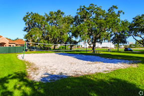 Kissimmee apartment for rent - A sandy volleyball court surrounded by trees and a green fence.