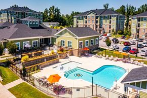 Raleigh-Durham apartment for rent - A large swimming pool surrounded by a fence and chairs at Foxwood Apartments, Raleigh-Durham, 27616