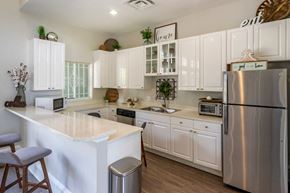 Orlando apartment for rent - Clubhouse kitchen with stainless steel appliances, white cabinetry, and hardwood flooring