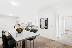High Point apartment for rent - Virtually staged dining room with marble table and green accent chairs. Kitchen and living room in background