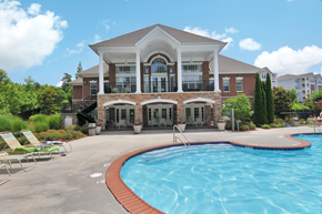 Buford apartment for rent - Community pool with pool furniture throughout. The clubhouse is in the background, surrounded by trees.