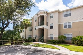 Fort Myers apartment for rent - Parking Lot and Walkway to Building Exterior with Trees and Courtyard Nearby