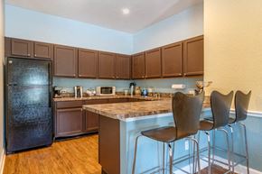 Naples apartment for rent - Clubhouse Kitchen with Brown Cabinets Black Appliances and Brown BarStools
