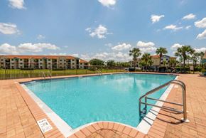Naples apartment for rent - Fenced in Swimming Pool and Sun Deck with Lounge Chairs with Palm Trees and Building Exteriors in the Background