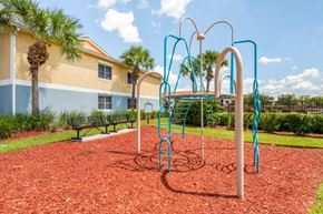 Naples apartment for rent - Playground with Green Accents on Mulch with Building Exterior and Benches with Treeline in the Background