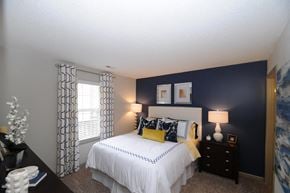 Gastonia apartment for rent - A bedroom with a white bed and a window with curtains.