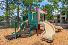 Jacksonville apartment for rent - Outdoor playground with seesaw, bench seating, surrounded by native landscaping