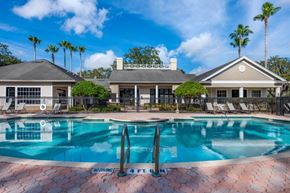 Orlando apartment for rent - Leasing Office Exterior with Swimming Pool and Sun Deck with Lounge Chairs with Trees in the Background
