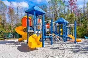 Orlando apartment for rent - Blue and Yellow Playground on Sand with Building Exterior and Trees in the Background