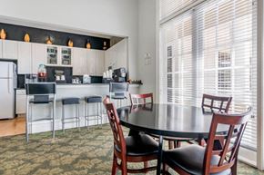 Orlando apartment for rent - Clubhouse Seating Area with Dining Room Tables in Front of Clubhouse Kitchen Bar with Barstools with Refreshments and Coffee on the Bar in Front of White Cabinets