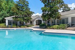 Jacksonville apartment for rent - Swimming pool surrounded by native landscaping and clubhouse in the background