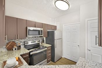 A kitchen with a refrigerator, oven, and microwave.