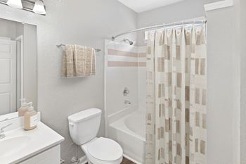 A white bathroom with a toilet, sink, and shower curtain.