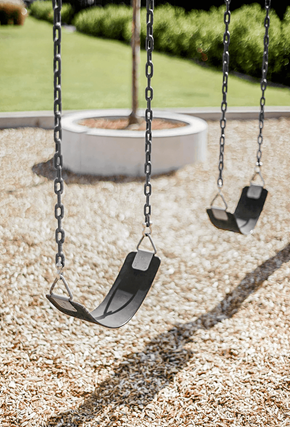 Denver apartment for rent - Two empty swings hanging from chains in a playground.