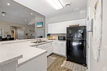 Tallahassee apartment for rent - A modern kitchen with a black refrigerator and white cabinets.