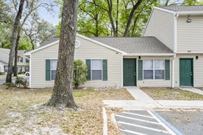 Jacksonville apartment for rent - a white house with green doors and a large tree in the front yard