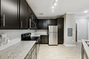 Canton apartment for rent - an empty kitchen with black cabinets and a stainless steel refrigerator