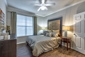 Nashville apartment for rent - A bedroom with a bed, a ceiling fan, and a nightstand with a lamp.