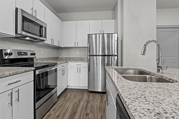 A modern kitchen with white cabinets and stainless steel appliances.