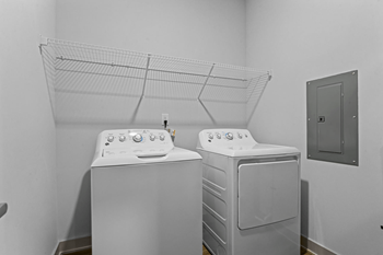 Two white front load washing machines in a laundry room.