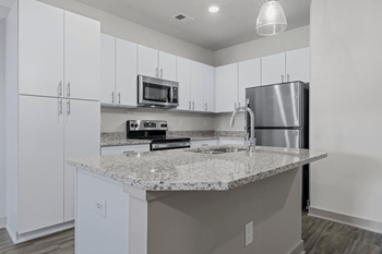 A kitchen with a granite countertop and stainless steel appliances.
