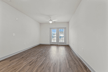 A room with wooden flooring and a window with blinds.