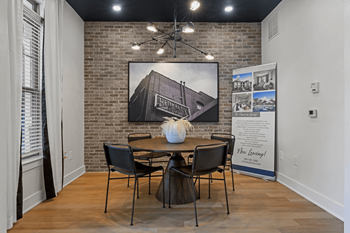 A room with a brick wall and a dining table set up.
