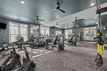 A gym with a variety of exercise equipment including treadmills, stationary bikes, and weight machines.